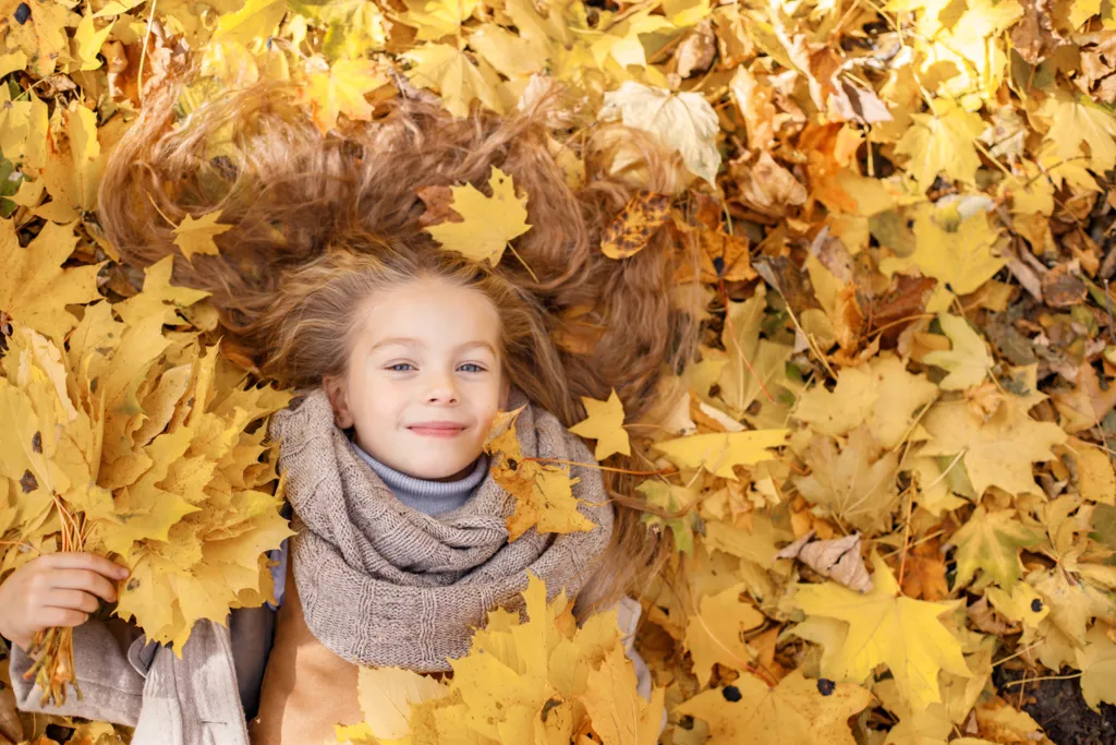 little-girl-fashion-clothes-autumn-forest-girl-lying-yellow-leaves-girl-wearing-brown-scarf-looking-camera.jpg